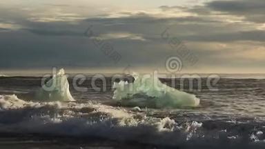 冰山和蓝白冰块在波浪上滚动。 波浪在冰上破碎。 日出时在海滩冲浪。 伊塞拉